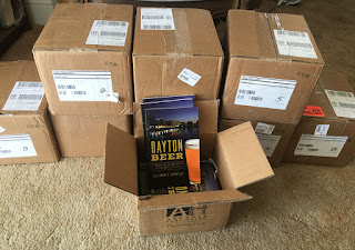 Photo of a stack of boxes containing 300 copies of Dayton Beer in my living room.