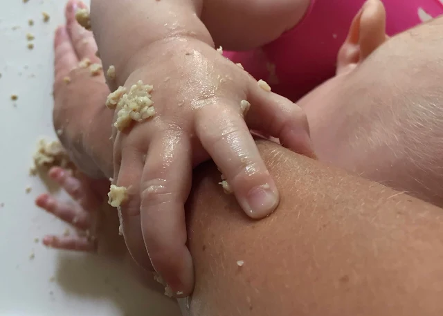 A baby covered in porridge grabbing on to a woman's arm and covering her in porridge