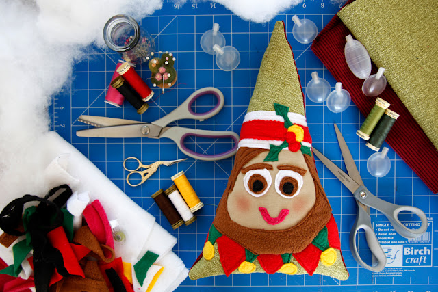 Homemade Christmas elf dog toy on a craft mat with sewing supplies