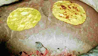 Cooking or roasting two Missi roti in a charcoal tandoor till crisp golden