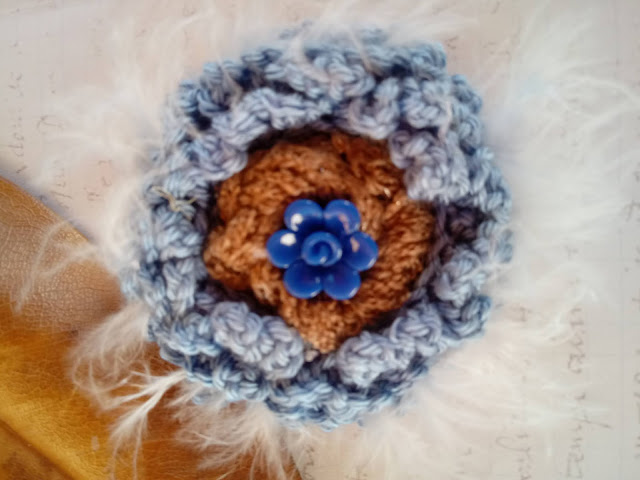 Flor de ganchillo en color azul tejano o vaquero, decorado con plumas y botón en forma de flor