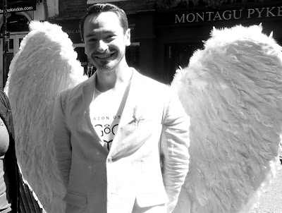 Blck and White photo of a young man dressed in white with white feather wings