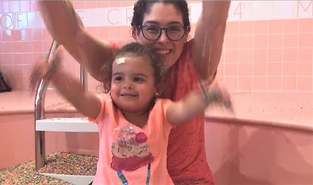 Mother and daughter play in a pool full of colorful sprinkles
