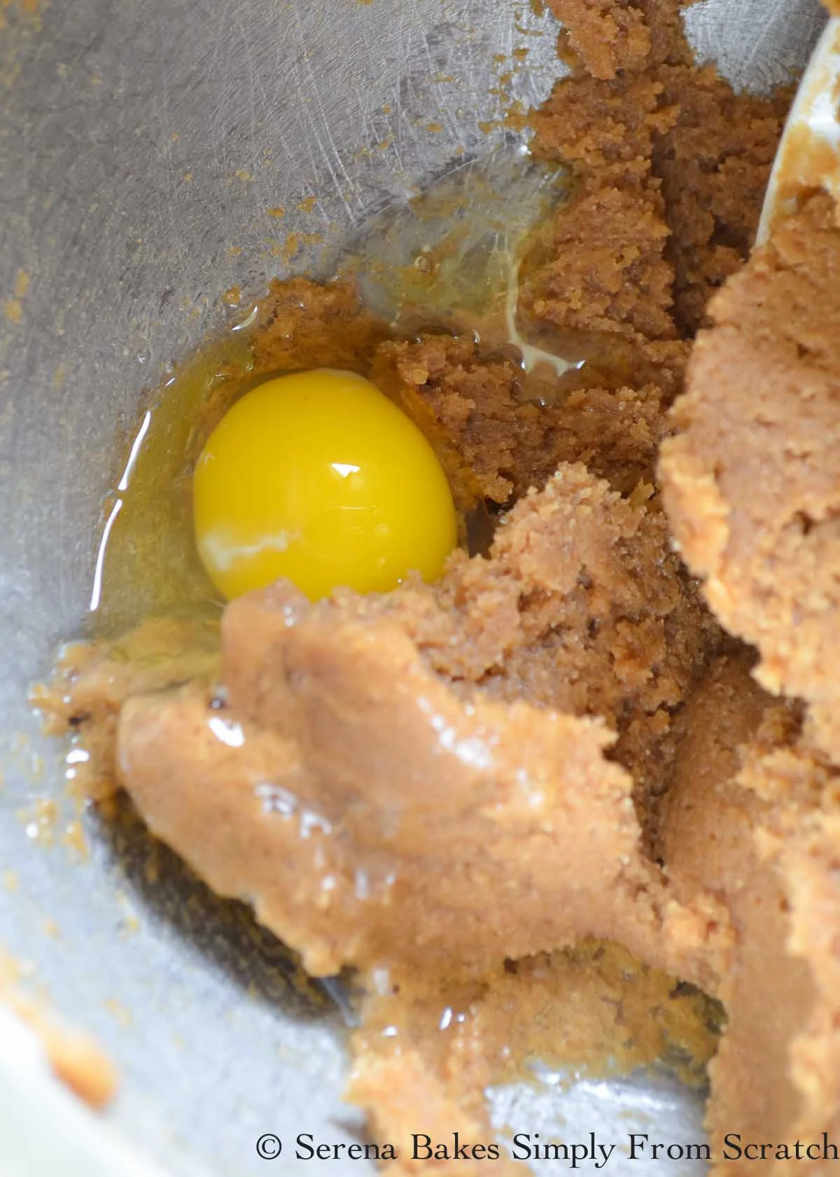 Whole egg being mixed into creamed sugar mixture.