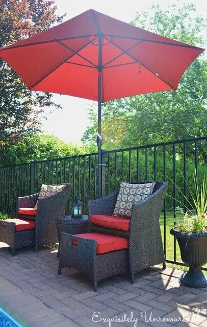 Chairs with red cushions and red umbrella by pool