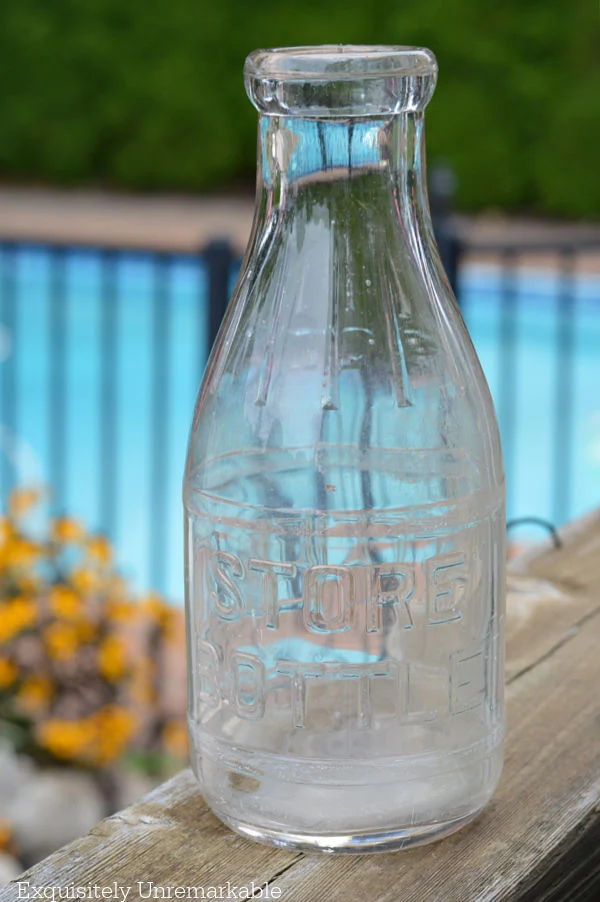 Glass Milk Bottle on a deck railing in garden