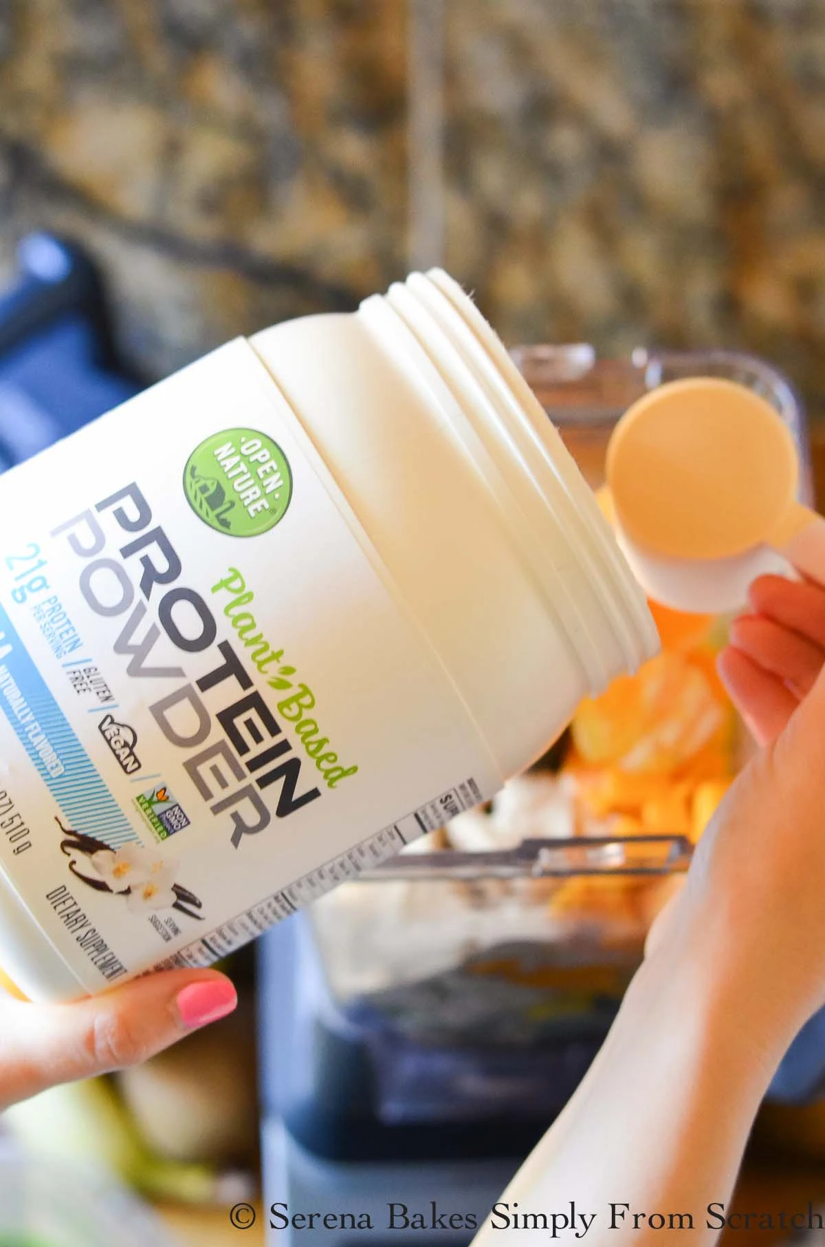 Open nature protein powder being scooped into a blender.