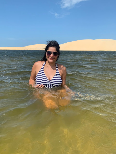 Passeio Quadriciclo em Parnaíba mulher morena, jovem, cabelo preto, oculos escuros, maio de banho listrado azul e branco em uma lagoa transparente