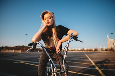 Chica rubia sentada en bici aburrida mirando a cámara