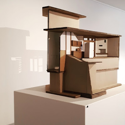 Cardboard model of The Paterson House designed by Enrico Taglietti, on a plinth in an art gallery with a red sticker on the plinth.