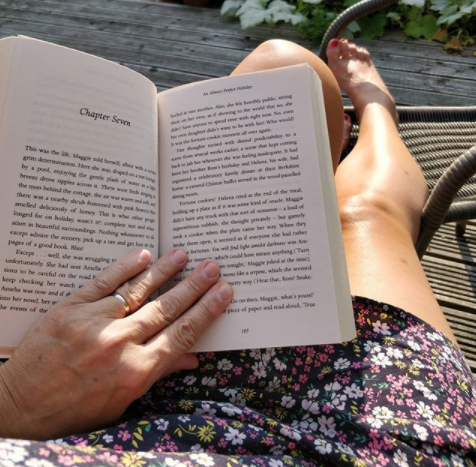 Enjoying a read and a finger in the sunshine.