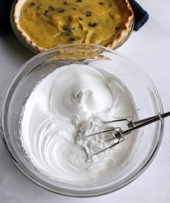 bowl of fluffy white meringue with pie crust filled with sour cream raisin filling in background