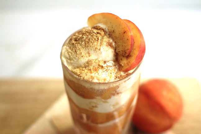 Easy Peach Pie Ice Cream Float contained in a tall, clear glass and topped with peach slices.
