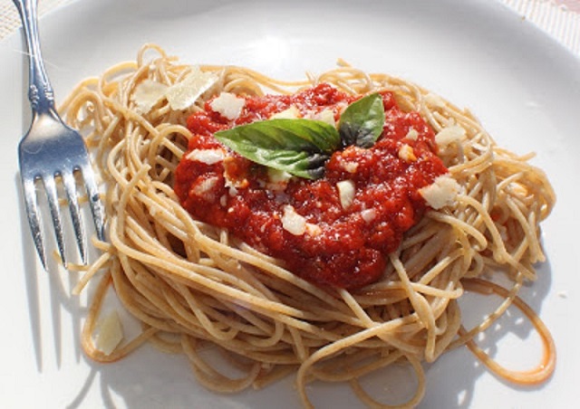 Simple Marinara Sauce homemade simple tomato sauce called marinara with all fresh ingredients over spaghetti sprinkled with cheese on a white plate some garlic herbs in a white plate with a fork