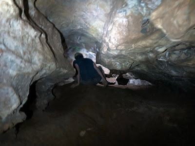 man going through tight opening in a cave