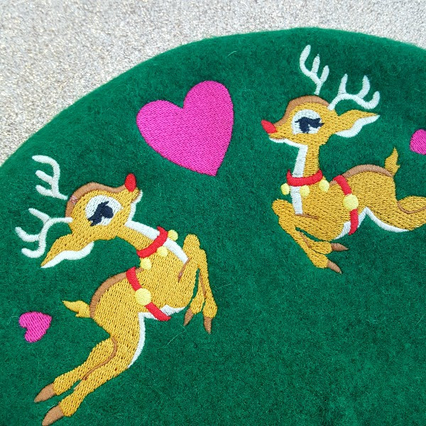 close up of Rudolph reindeer embroidered on green wool beret hat