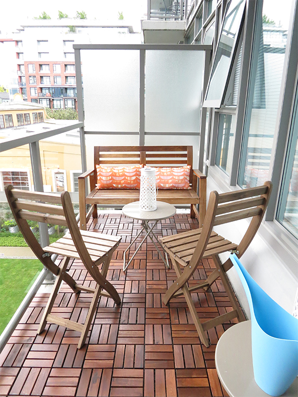 Vancouver city condo apartment small space patio makeover using IKEA finds: Runnen wood tiling, Applaro bench, Askholmen folding wooden chairs, white Solvinden LED solar-powered table lamp