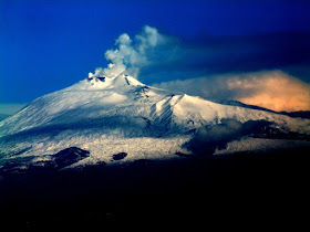 The mighty Mount Etna, smoke emerging from its snow- capped peak, dominates eastern Sicily