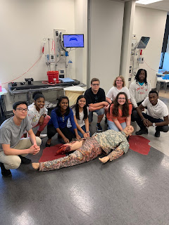 Students are grouped around a simulation mannikin during the Stop the Bleed training