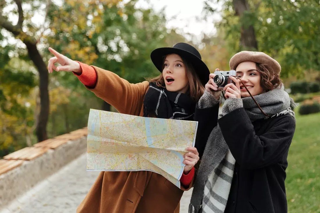 Duas meninas felizes com um mapa e uma camera na mao