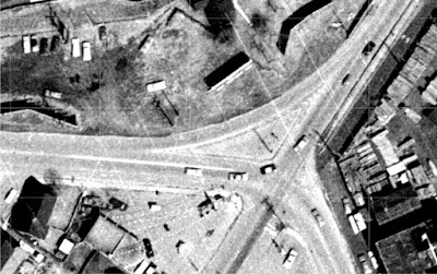 Overhead black-and-white photo of the Wellington/Bayview/Bayswater intersection with the three buildings gone and a much larger triangle between the slip lane and the intersection.