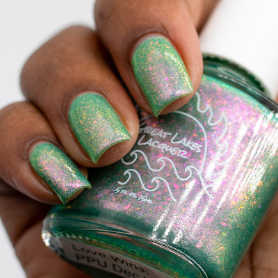 green nail polish with pink to green shifting flakes and shifting shimmer on dark skin