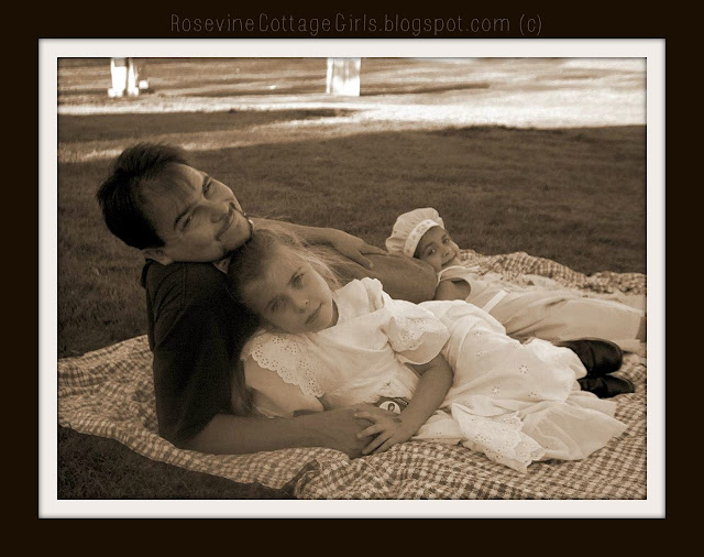 Sweetness of the fleeting moments - A father and two daughters reclining on a blanket at a picnic.  They look at the camera and enjoy the music being played and a beautiful summer day. 