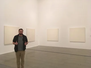 Man posed in front of modern art canvases that appear to be blank