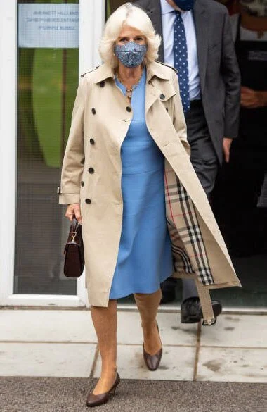 Camilla, Duchess of Cornwall wore a blue wool midi dress, and the mid-length chelsea trench coat from Burberry. British luxury brand Burberry