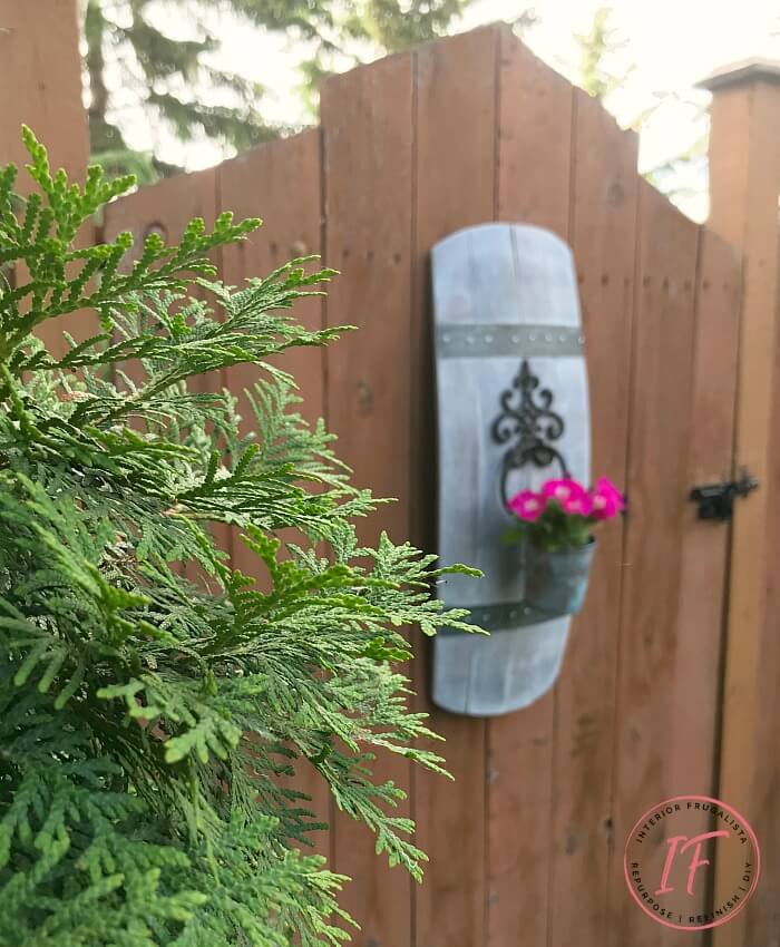 A unique barrel stave outdoor wall planter idea using a repurposed stave and wrought iron door knocker for a one-of-a-kind hanging flower planter.