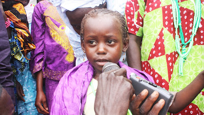 Aja speaking about human rights and health at an inter-village meeting in her community