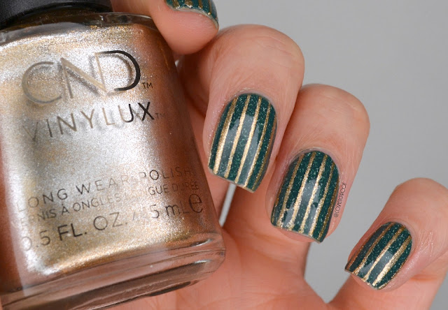 photo of green and gold striped nail art holding gold polish bottle