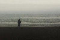 Blurry monochrome photo of a  silhouetted figure against the sea