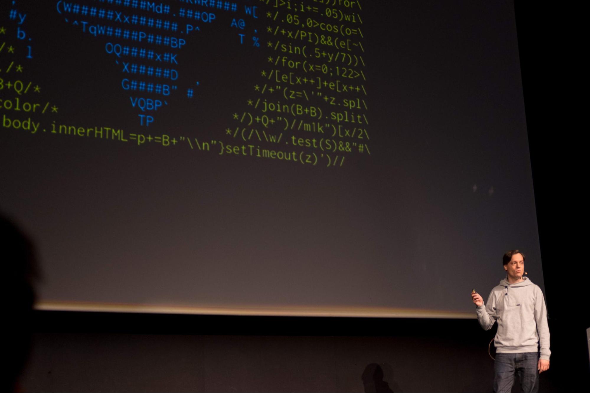 Image shows Martin Kleppe presenting onstage. A large projector screen displays code behind him
