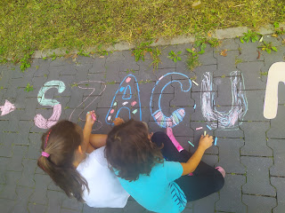 Dzieci rysujące kredą napis szacunek na chodniku.