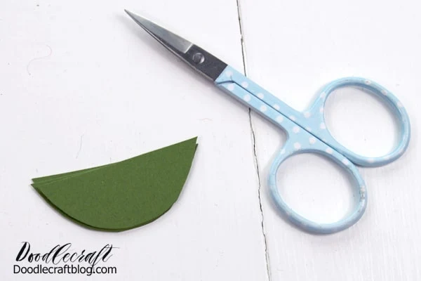 use the scissors to cut the green ears out of cardstock in a half circle shape.