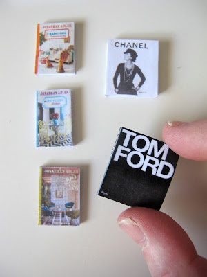 Selection of five modern dolls' house miniature books on design, one of which is being held between a finger and a thumb.