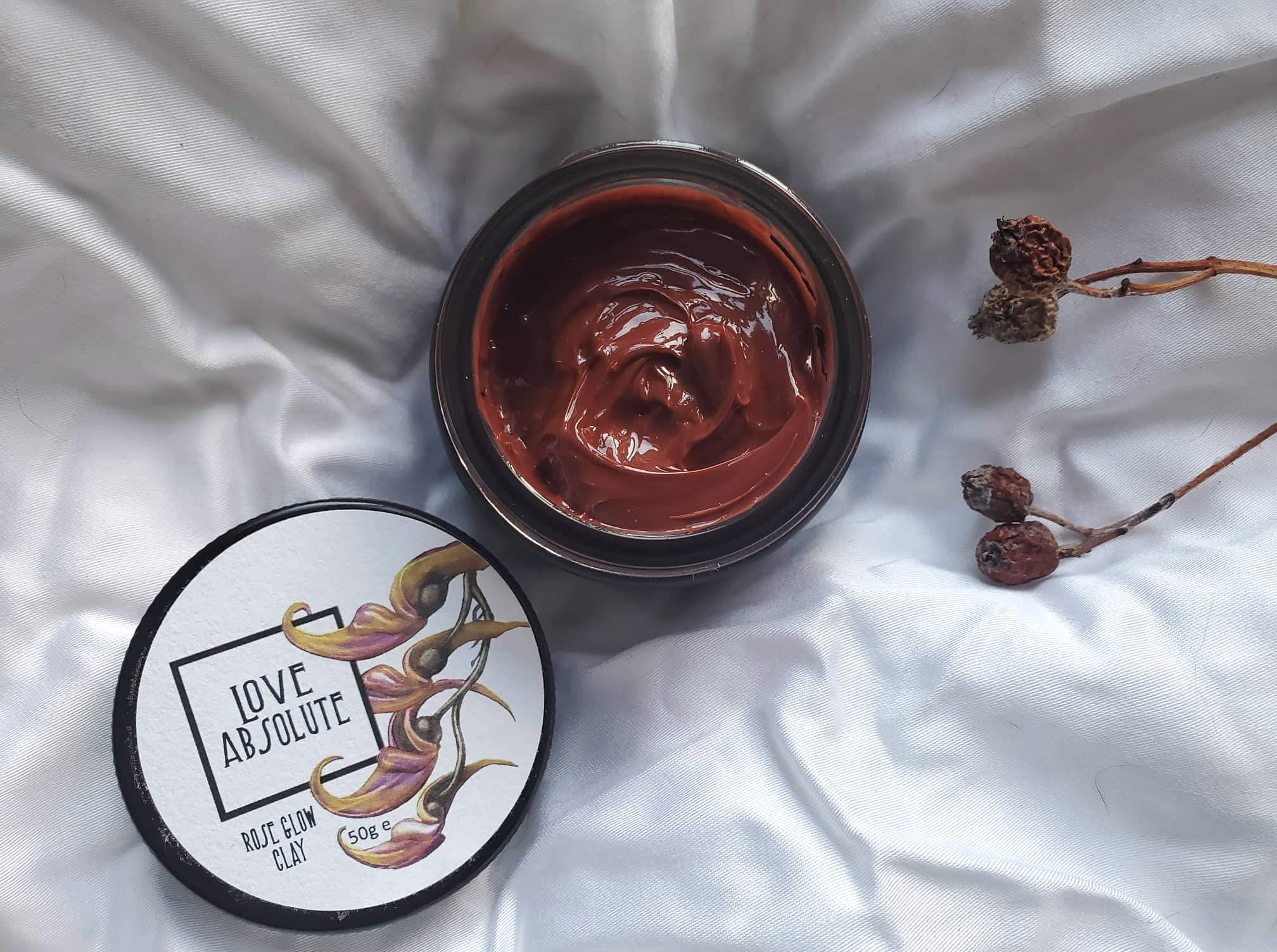 open jar of Rose Glow Clay Balm Mask from Love Absolute with a rich reddish brown texture