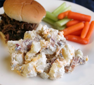 serving of potato salad on plate with pulled pork sandwich and veggies