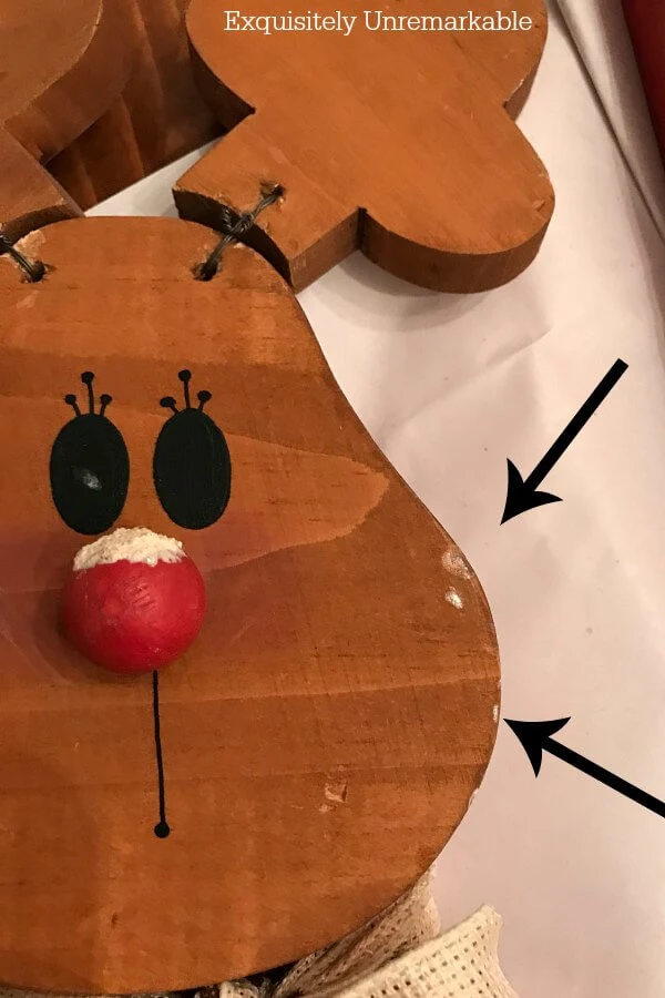 Chipped Wooden Reindeer Face with arrow marking the spot