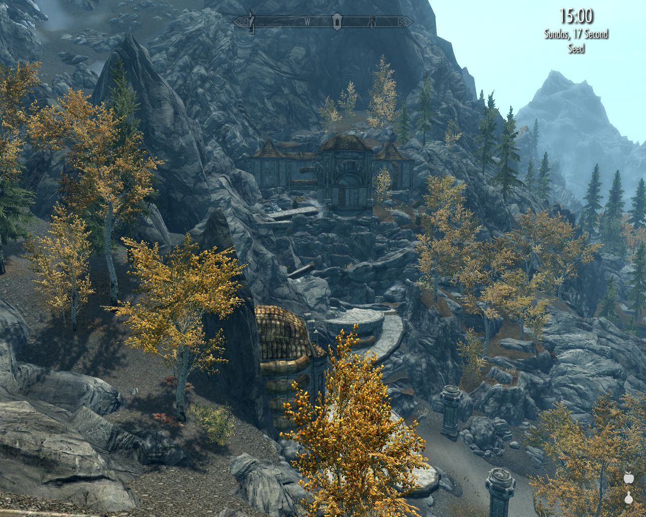 view down a rocky mountain slope, Dwemer structures below and ahead, many trees, clear blue sky
