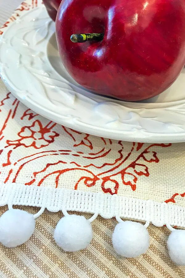Apple on red plate and red fabric with ball fringe