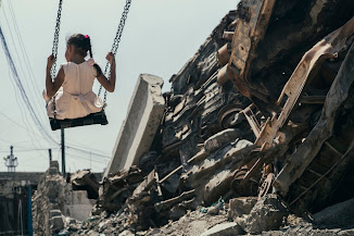 فتاة تلعب على الأرجوحة بجانب مبنى مدمّر