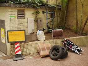 broken seat, worn tires, and broken baby stroller at trash collection point in Macau