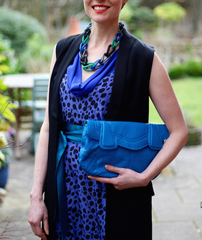 Fake Fabulous | Electric blue jumpsuit, blue clutch, green shoes, black coat and a chunky necklace.