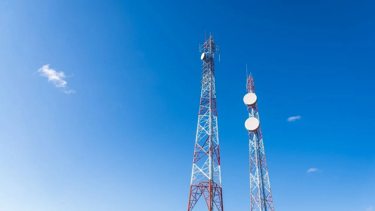 Colorful mobile phone network telecommunication towers against blue sky background. Concept of telecom, telco, connectivity, and technology.