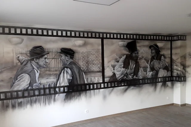 Malowanie obrazu na ścianie w pokoju telewizyjnym, artystyczne malowanie ściany w motyw z filmu Janosik, grafika w sali telewizyjnej