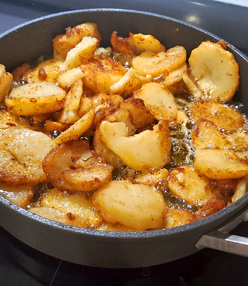 this is a pan of oil sizzling home fried potatoes with Italian seasonings