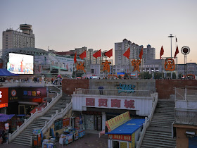 Chinese flags on the main sign for the Guomao Shopping Center (国贸商城) at Culture Square (文化广场) in Mudanjiang, China