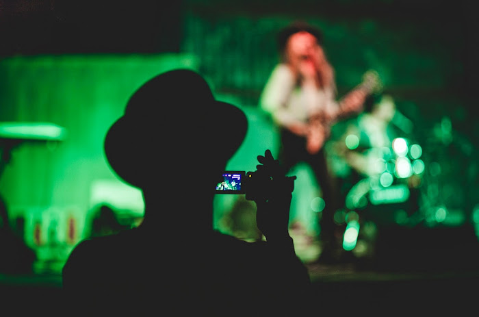 Fan photographing a musician at a live event